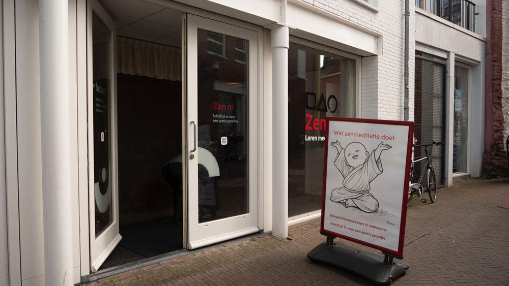 een klinkerstraat in Deventer met een witte gevel, op het raam is het Zen.nl logo te zien